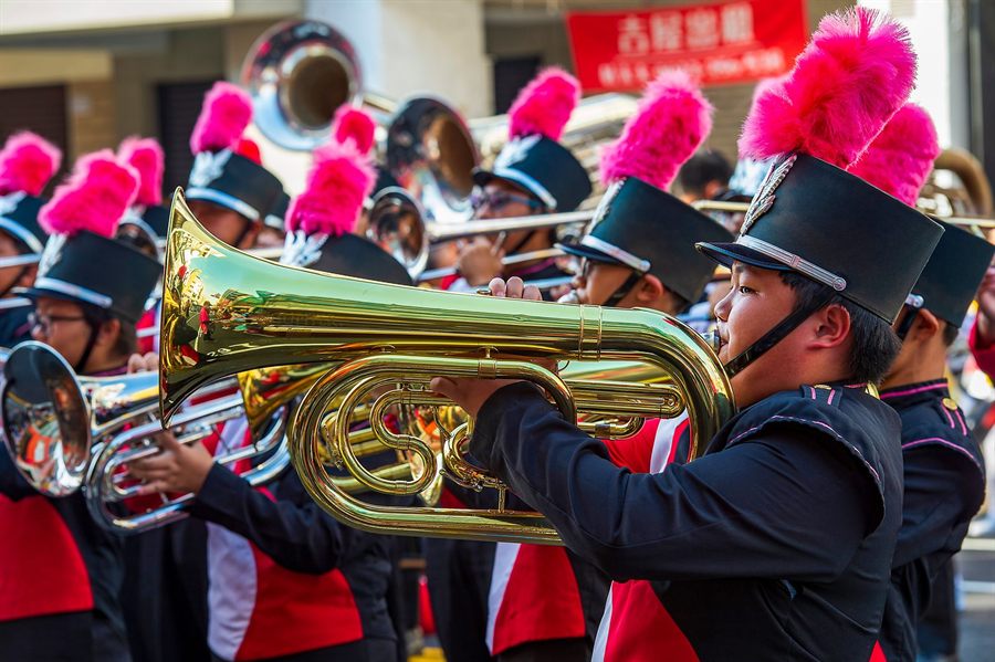 Youth brass band playing tubas and horns in plumed hats