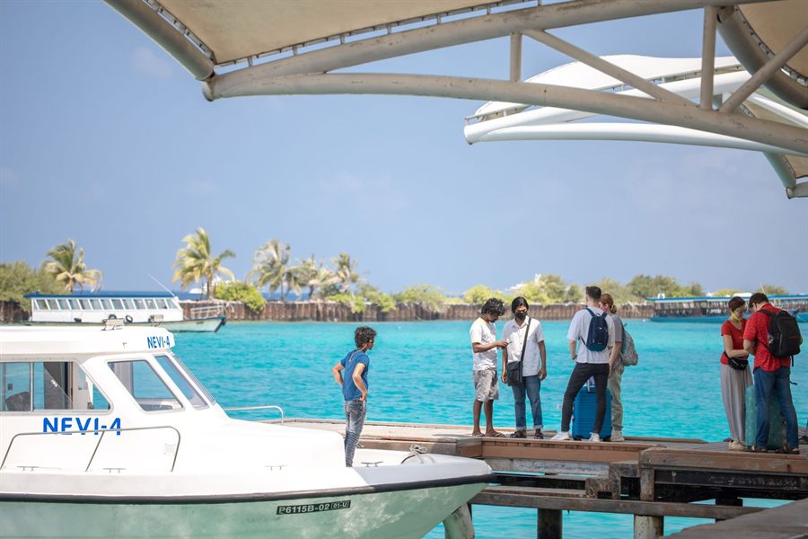 Young travelers with backpacks on a tropical pier beside a boat and turquoise water