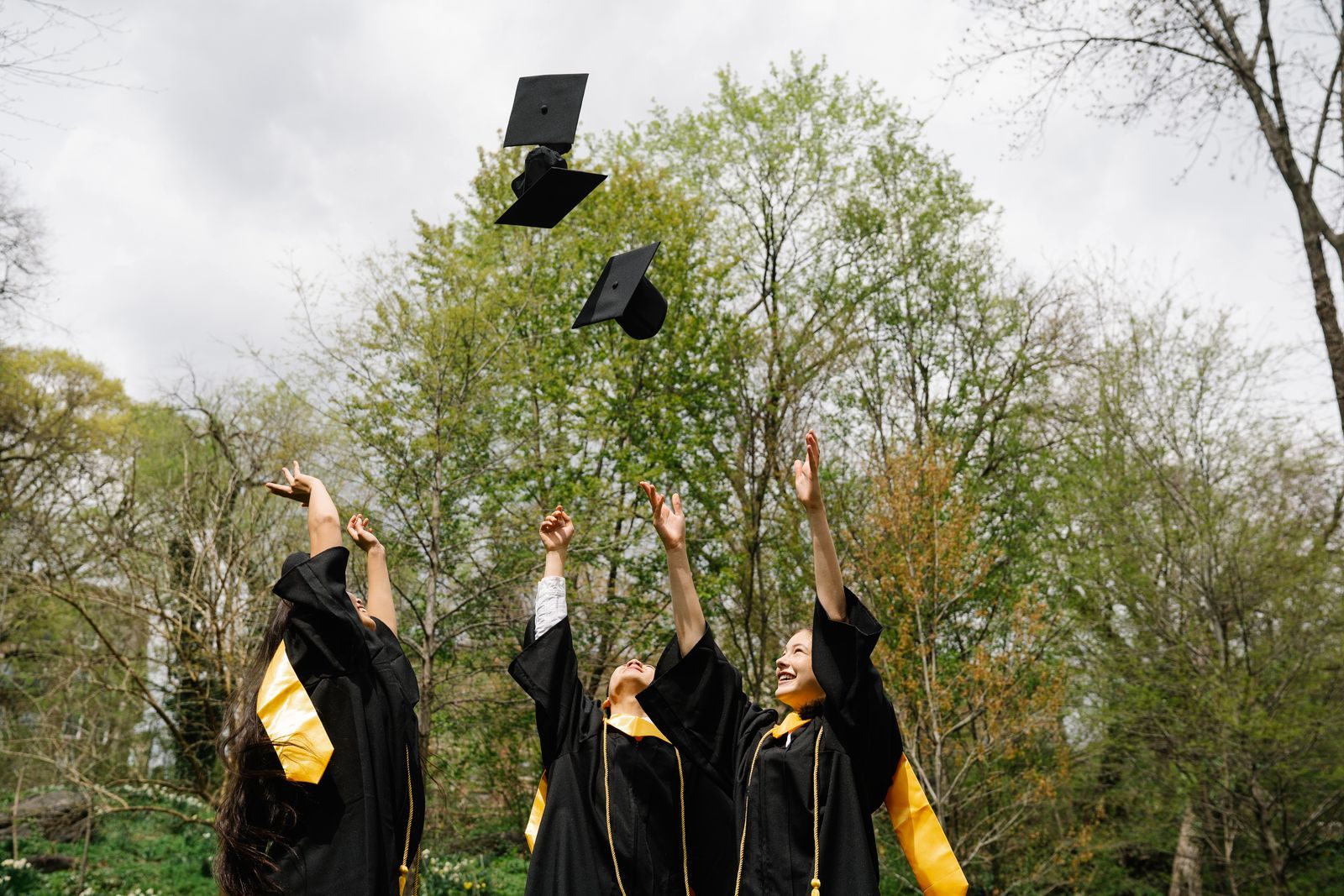 Graduates in gowns tossing their caps into the air outdoors, ready for a high school senior trip cruise
